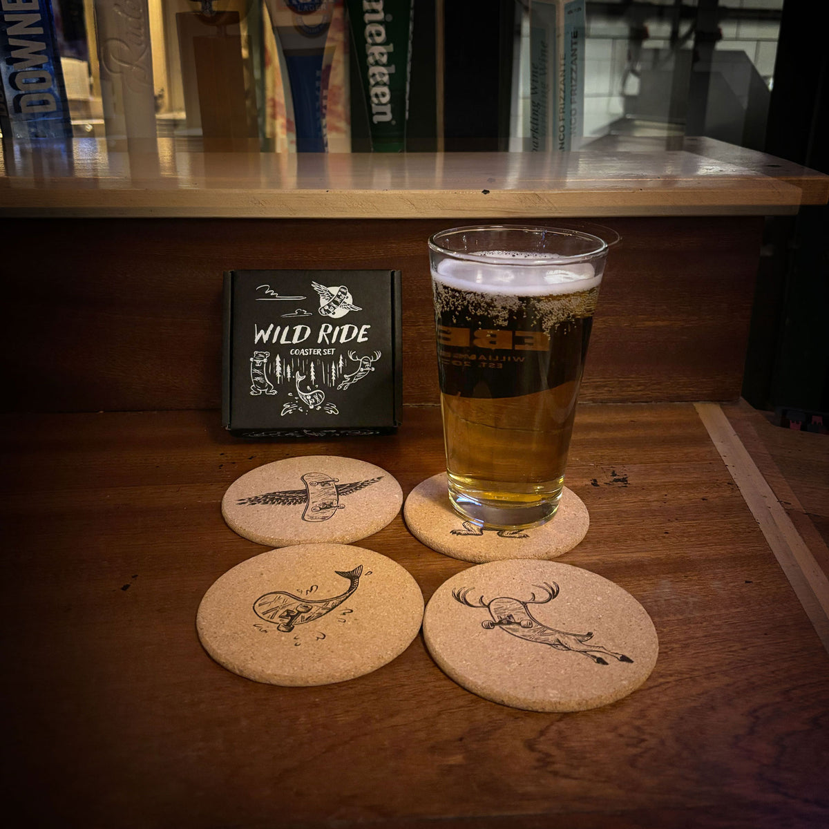 Cork coasters with skateboard and animal illustrations shown under a glass